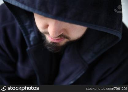 young man with face half concealed by his hood