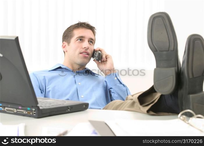 Young Man With Feet on His Desk Working on Laptop