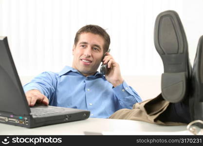 Young Man With Feet on His Desk Working on Laptop