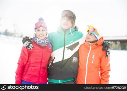 Young man with female friends standing arm around in snow