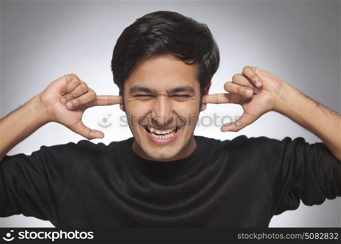 Young man with fingers in his ears