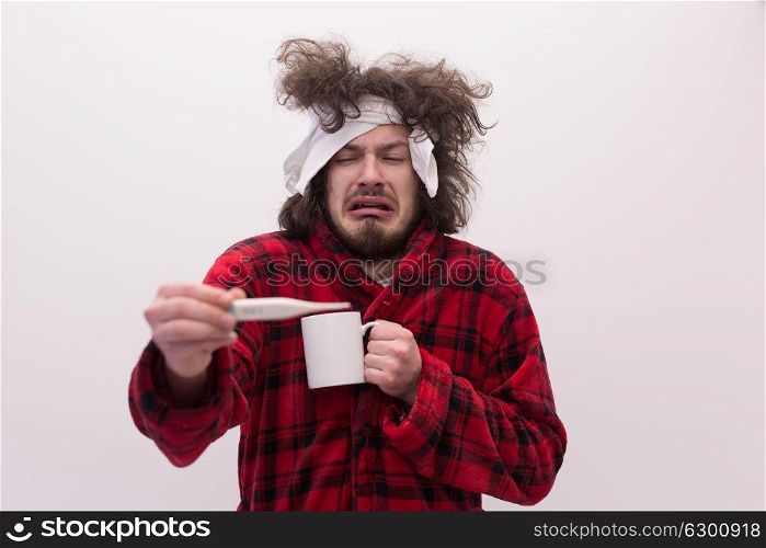young Man with flu and fever wrapped holding cup of healing tea isolated over white