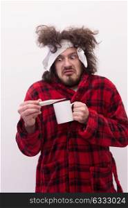 young Man with flu and fever wrapped holding cup of healing tea isolated over white