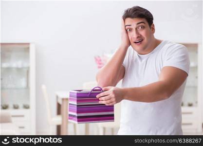 Young man with gift bag at home preparing suprise for wife