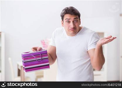 Young man with gift bag at home preparing suprise for wife