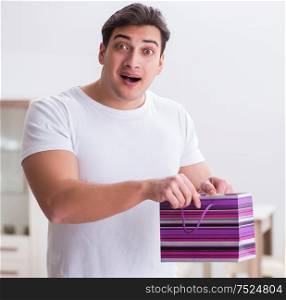 Young man with gift bag at home preparing suprise for wife. The young man with gift bag at home preparing suprise for wife