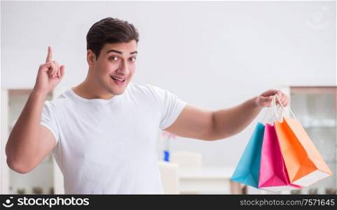 Young man with gift bag at home preparing suprise for wife. The young man with gift bag at home preparing suprise for wife