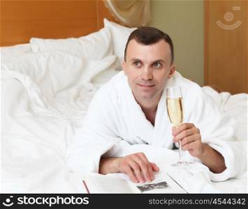 young man with glasses of champagne in bed