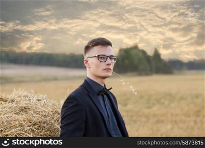 Young man with glasses thinking and standing on the field, vintage instagram toning&#xA;