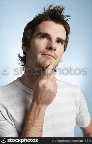 Young man with hand on chin looking up