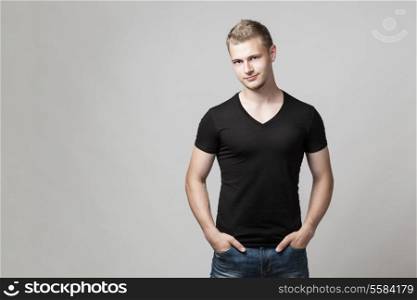 young man with hands in pockets isolated on gray background with copyspace