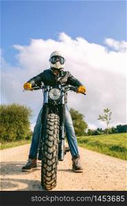 Young man with helmet riding a custom motorbike outdoors. Man with helmet riding custom motorbike