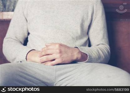 Young man with his hands resting on his belly is relaxing on sofa