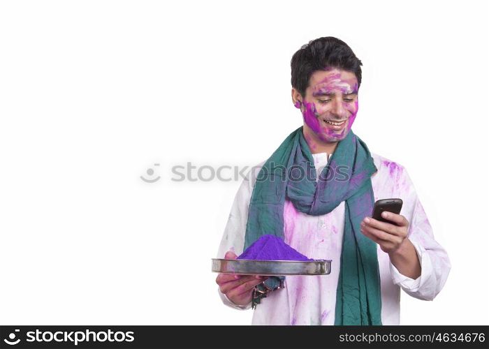 Young man with holi colour reading an sms