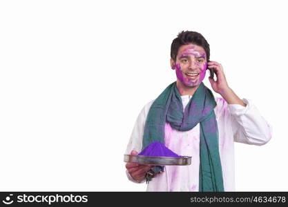 Young man with holi colour talking on a mobile phone