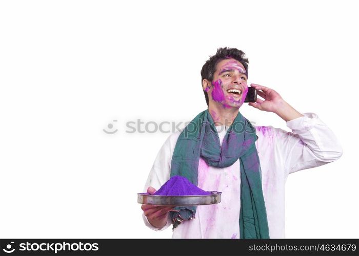 Young man with holi colour talking on a mobile phone