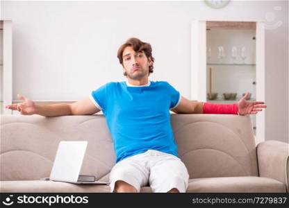 Young man with injured arm sitting on the sofa 