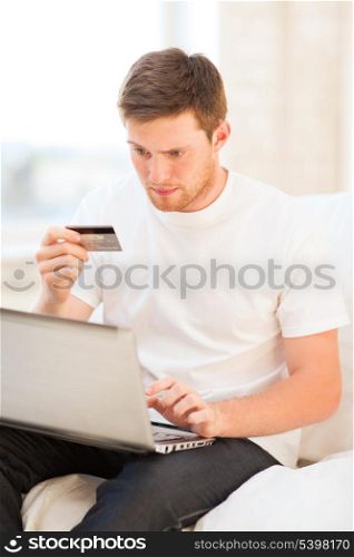 young man with laptop and credit card at home