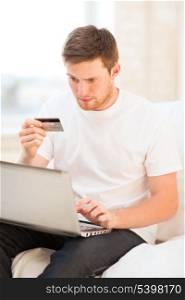 young man with laptop and credit card at home
