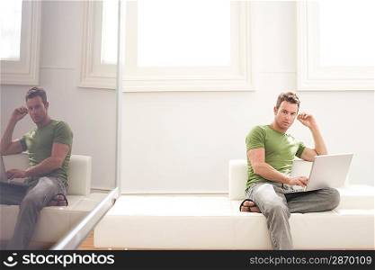 Young man with laptop on sofa