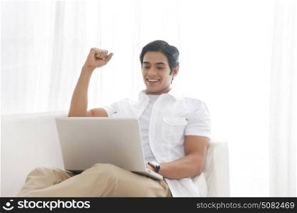 Young man with laptop rejoicing
