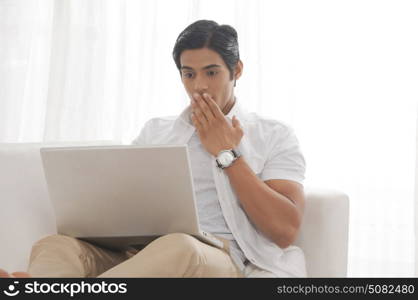 Young man with laptop shocked