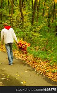 Young man with leaves in his hand walking in the woods in autumn