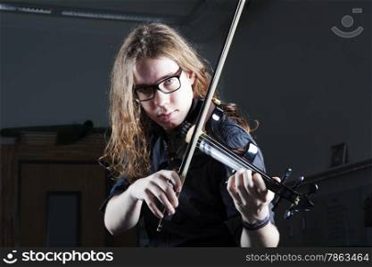 young man with long hair and glasses plays electric violin with harsh light