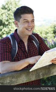 Young Man With Map Hiking In Countryside
