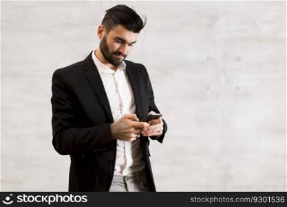 Young man with mobile phone by the wall