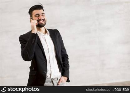 Young man with mobile phone by the wall