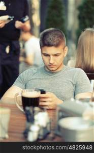 Young man with mobile phone in outdoor restaurant