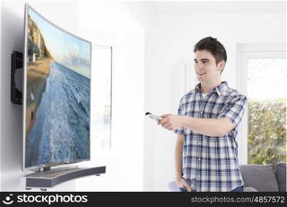 Young Man With New Curved Screen Television At Home