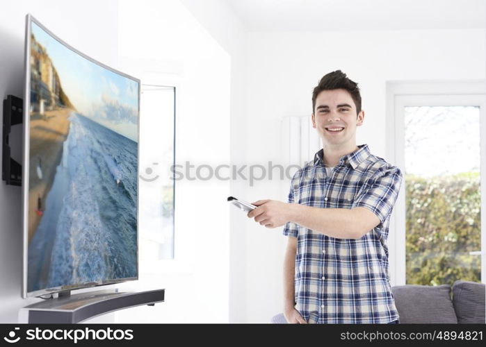 Young Man With New Curved Screen Television At Home