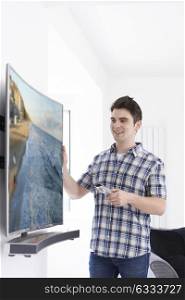 Young Man With New Curved Screen Television At Home