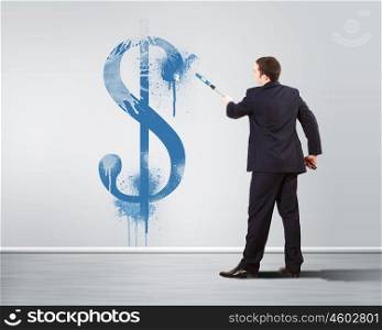 Young man with paint brush and banknote painted on the wall