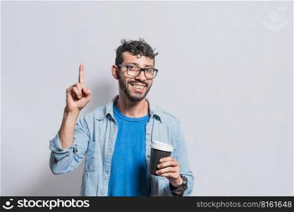 Young man with paper coffee cup pointing finger up, Happy smiling person with paper coffee cup pointing finger up