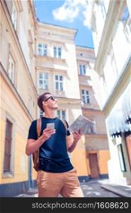 Young man with phone gid and city map in Vienna street. Man tourist with a city map and backpack in Europe street. Caucasian boy looking with map of European city.