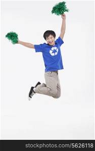Young man with recycling t-shirt cheering with pompoms, studio shot
