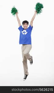 Young man with recycling t-shirt cheering with pompoms, studio shot