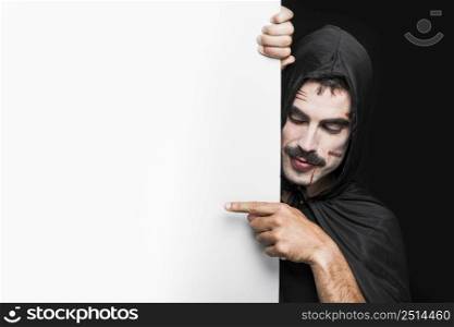 young man with scratches face black cloak with hood posing studio