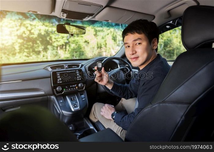 young man with smart key remote in a car