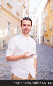 Young man with smartphone in Vienna street. Caucasian boy looking at camera outdoor. Man tourist with cellphone in Europe street. Caucasian boy looking at camera outdoor