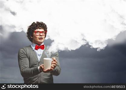 Young man with smoke coming out of cup. Young man with smoke coming out of a cup experimenting