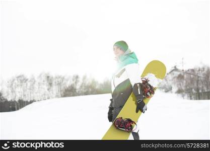 Young man with snowboard walking in snow