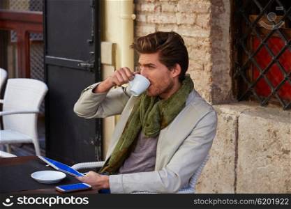 Young man with tablet pc touch in an cafe outdoor having some coffe cup