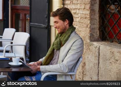 Young man with tablet pc touch in an cafe outdoor having some coffe cup