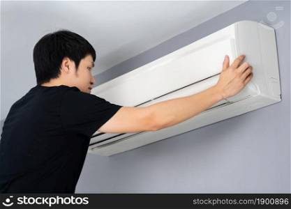 young man with the air conditioner indoor at home