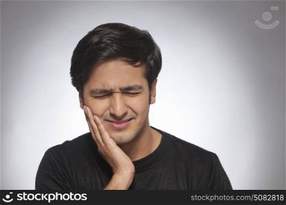 Young man with toothache and hand on cheek