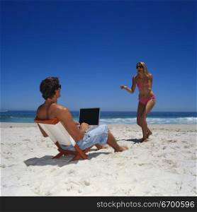 Young man working on a laptop at the beach